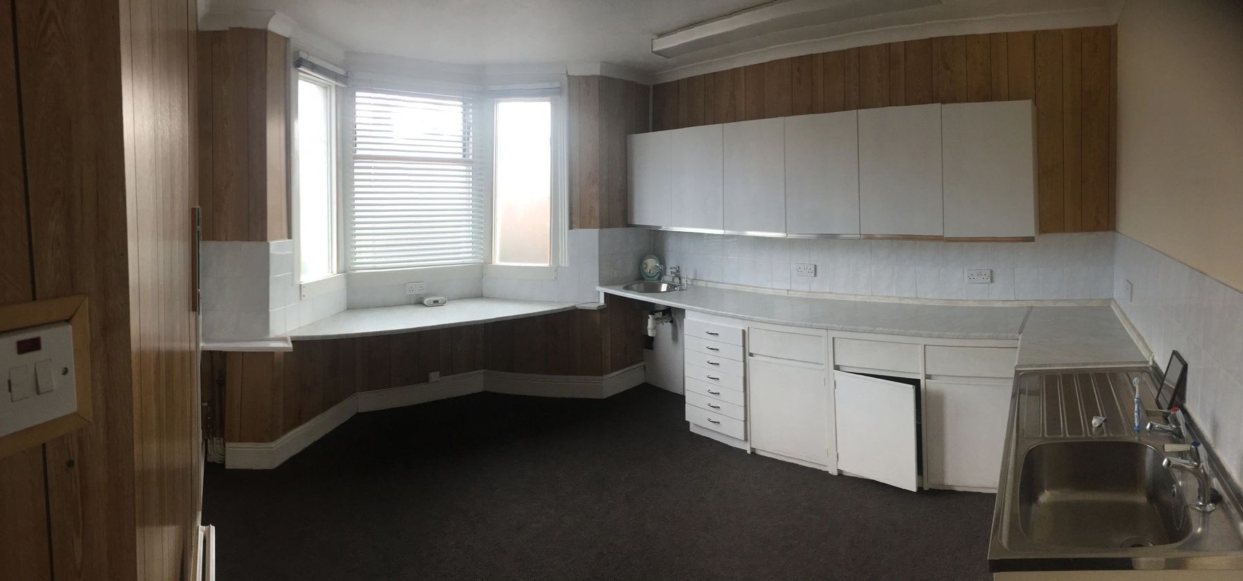 The bay-window room as the old dentist practice, with fitted cabinets and a steel sink